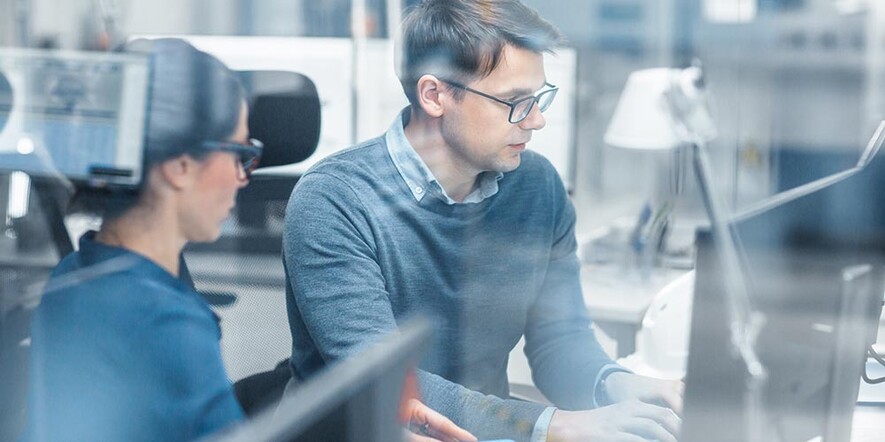 Woman and man working in front of a monitor